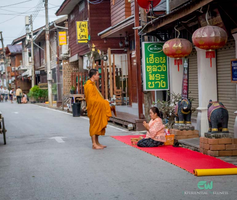 A local woman gives alms to a Buddhist monk in Chiang Khan