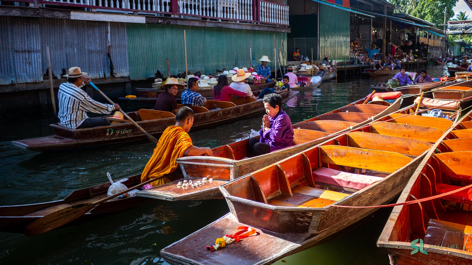 Local people is receiving the bless from Buddhist Monk on the boat in Damnoen Saduak Floating Market